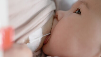 Mother breastfeeding baby with SNS system. Close up view