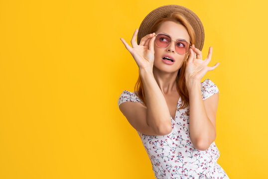 young woman in straw hat and sunglasses on yellow background
