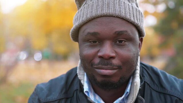 African american man in winter hat with sad smile looks at the camera, close-up shot