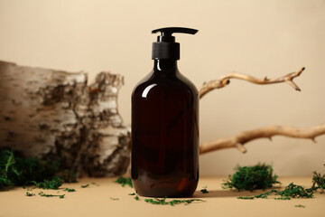 Dark pump dispenser bottle with natural shampoo. Tree branch, bark birch, moss on background.