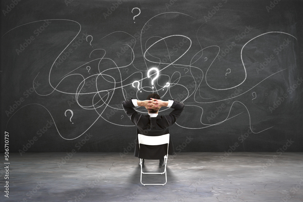 Aufkleber Find solution and making choice concept with back view on businessman sitting on chair and looking at blackboard with question marks and chaotically written lines