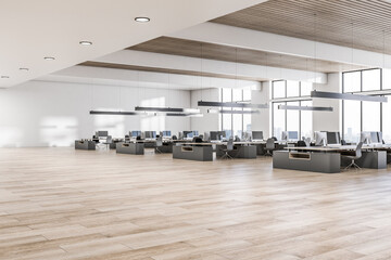 Perspective view on sunny spacious coworking office with dark modern work places with computers, lamps hanging from wooden slatted ceiling, white walls and city view from big windows. 3D rendering