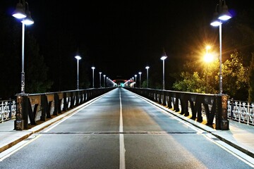 Old Iron bridge with riveted joints over the Ebro River at night in the city