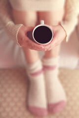 Fototapeta na wymiar The girl holding the mug of hot coffee in her tender hand. in the morning soft sunlight.