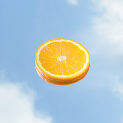 A slice of orange and a blue sky. Summer outdoor minimal fruit concept.