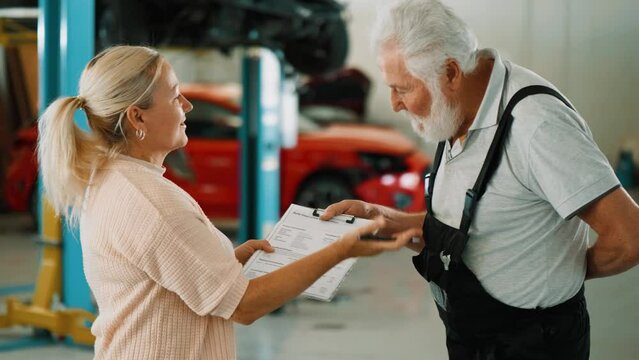 Medium shot of female client signing document and shaking hand with auto mechanic after leaving his car for repairs