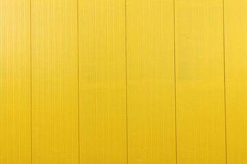 Yellow metal tile fence background. Fence from corrugated board. Yellow slate background. Yellow zinc metal sheet texture. Steel panel of the enclosing wall.	