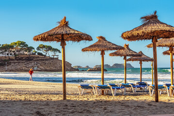 deserted morning sea beach with sunny screens. Platja Palmira