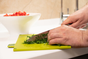 Obraz na płótnie Canvas finely chopped dill for salad preparation with a kitchen knife