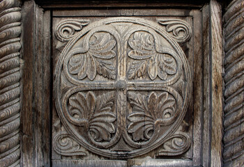 weathered wooden ornament with engraved decorative natural motifs inside a circle - old lacework on a door of wood with a frame for an ancient background