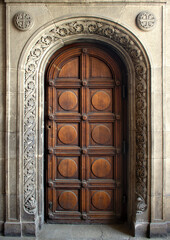 big beautiful ornate wooden door, framed by a decorated stone arch - entrance to a gothic cathedral...