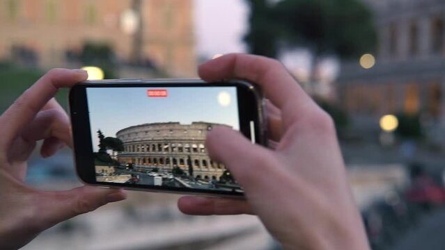 Tourist takes a smartphone video of the Colosseum in Rome Italy .
