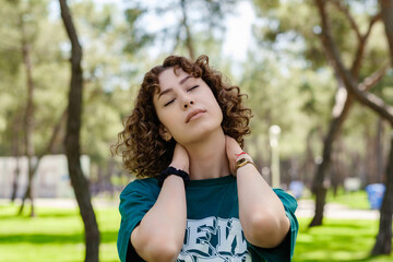 Beautiful redhead woman wearing green tshirt standing on city park, outdoor enjoying fresh air outdoor, relaxing with eyes closed, feeling alive, breathing, dreaming.