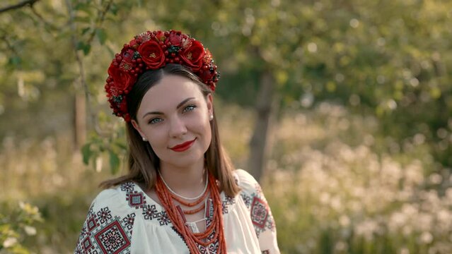 Attractive ukrainian woman in traditional embroidery vyshyvanka dress, ancient coral beads and red flowers wreath. Ukraine, freedom, culture, national costume