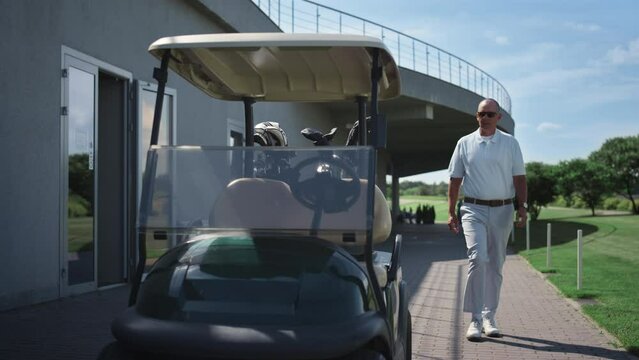 Rich golf player walking in driving cart. Luxury old man sit at country club.