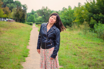 a beautiful woman with black long hair stands on a path in the park.