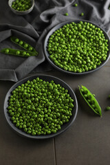 Fresh green peas in plates on a gray background. 