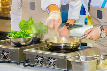 The chefs work in the restaurant's kitchen. Cooks fry vegetables in a frying pan. Cooking vegetable dishes. Vegetarian cuisine. Vegetable side dishes. Vegetable dishes. The cook's job.