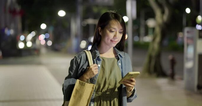 Woman walk in the street at night with her cellphone