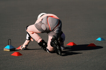 A girl roller skater in protection gets up on roller skates after a fall. Failure in training.