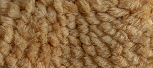 Short smooth beige llama fur texture in the form of a knitted product. Close-up