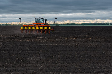 Fototapeta premium A tractor with a seed drill is engaged in planting grain and fertilizing.