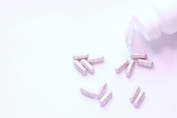 Gray pill capsules and pill bottles were placed on a white table.