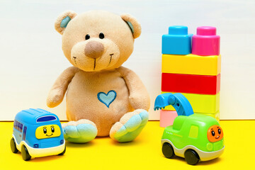 teddy bear with colorful constructor, toy blocks, cars for children play on white yellow background, baby's childhood development, Educational logic toys for toddler kid's concept