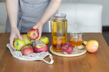 Young woman and fresh homemade organic apple juice or cider on a wooden table in a glass jug
