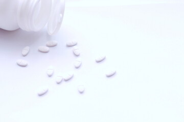 White pills and pill bottles were placed on a white table.