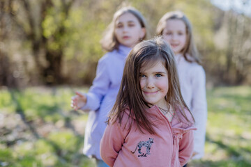 Fototapeta na wymiar Three little sisters looking at camera in spring nature together.
