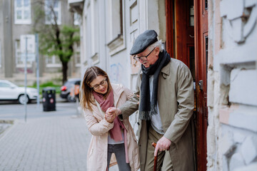 Obraz premium Adult daughter taking her senior man for a walk in town.