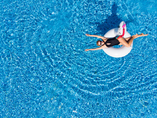 Aerial top view from drone of woman on unicorn pool float in pool in hotel.