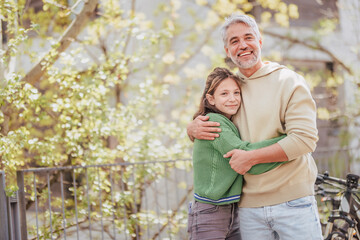 Teenage daughter hugging her father outside in town when spenidng time together.