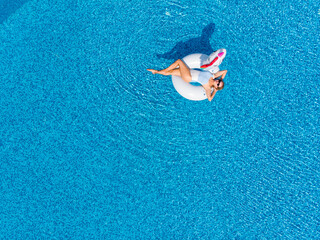 woman on unicorn pool float in pool in the hotel. Summer holidays. Aerial top view from drone