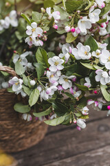 Spring time. A beautiful bouquet of flowering apple branches in a wicker basket on a wooden table in the spring garden. The concept of spring and holiday. A copy of the text space.