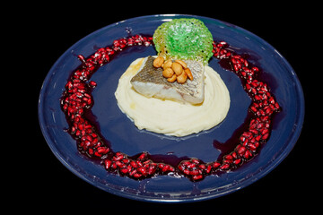 Fish fillet on a blue plate with sauce and pomegranate seeds. Fish dish in a restaurant