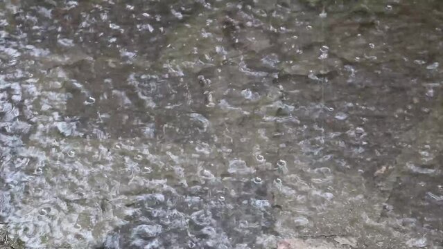 strong storm with water drops making ripples on a street puddle covering a cobblestone of the old town - close up effect