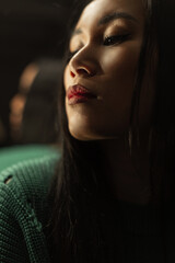 Fototapeta premium Stylish female portrait of a beautiful young girl with an Asian face in the dark