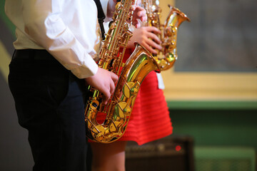 Two saxophonists playing a musical instrument saxophone a man and a woman in a red dress background...