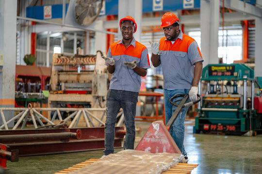 african American male worker in a production line is dragging a cart inside the factory to carry out distribution work to a distribution center to serve customers.