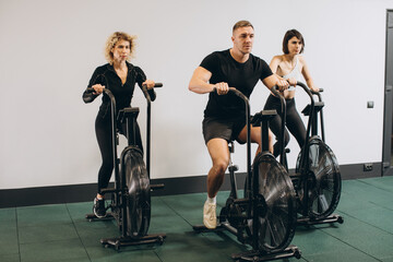 Fototapeta na wymiar Young man and women using air bike for cardio workout at cross training gym