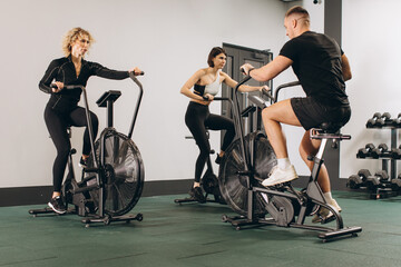 Young man and women using air bike for cardio workout at cross training gym