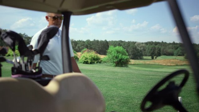 Luxury golf sportsman walking to golfing car. Rich guy sit cart at country club.