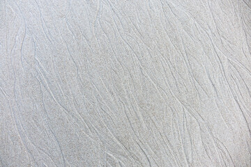 Sand background and texture. Wet beach sand texture after low tide. Sand with wave print. Ripple on the beach sand. 