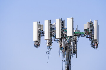 Close up of telecommunications cell phone tower with wireless communication antennas; blue sky background and copy space on the right
