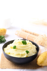 Mashed potato with pasley in black bowl on white background