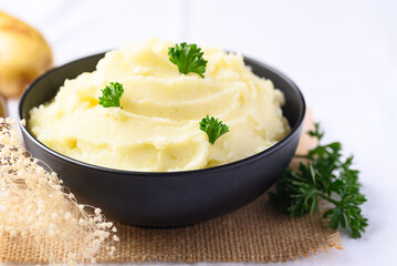 Mashed potato with pasley in black bowl on white background