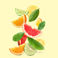 Fresh juicy citrus fruits and green leaves on beige background