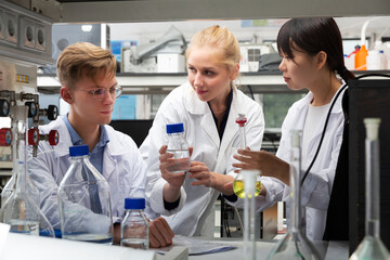 Fototapeta premium Interior of modern chemical laboratory with international group of young scientists using lab equipment during research .